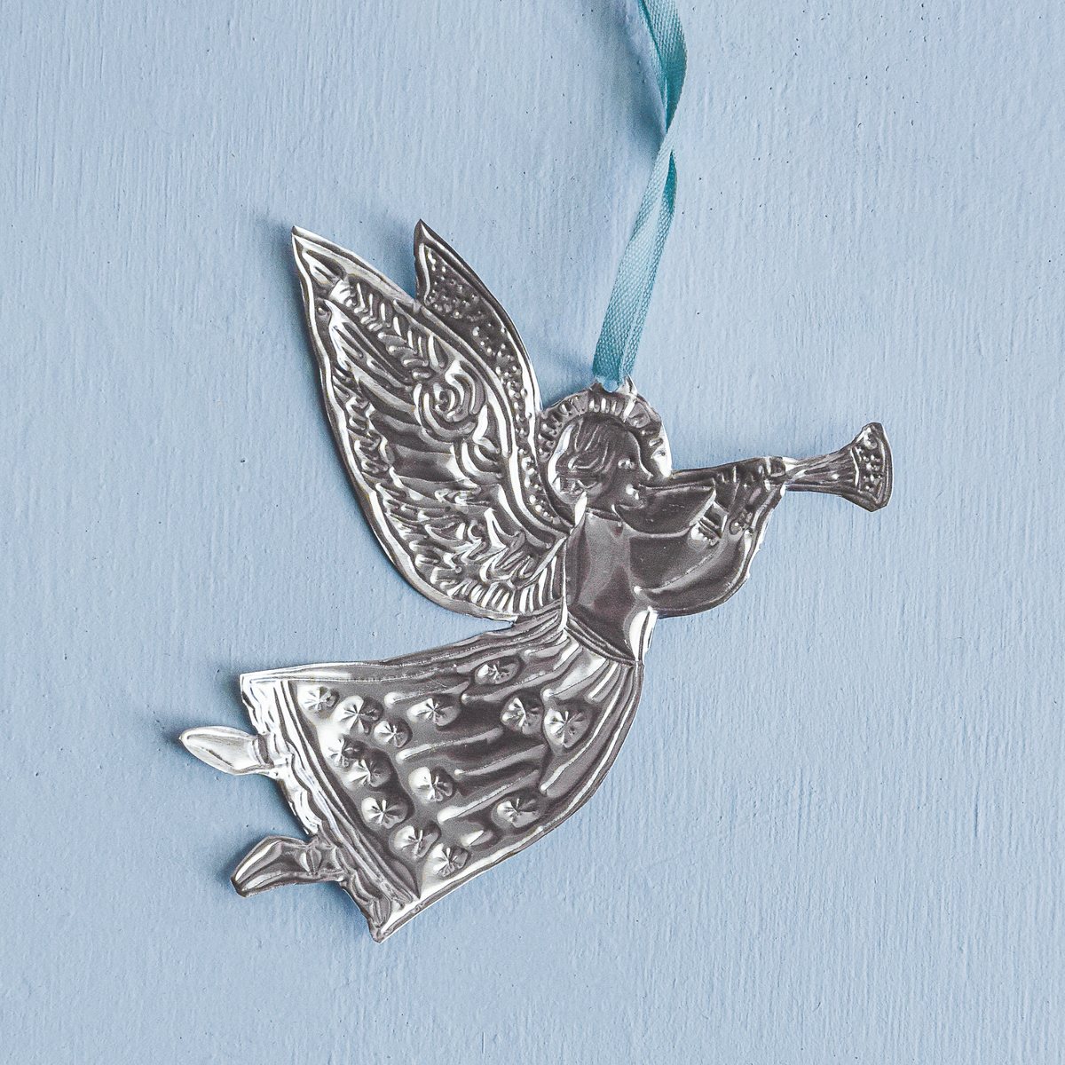 Silver angel ornament with a blue ribbon on a light blue background