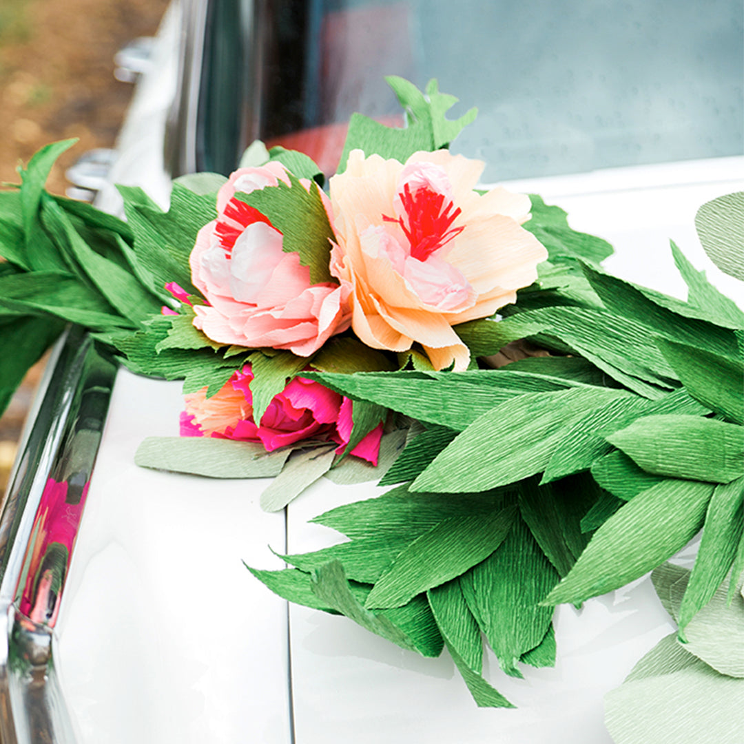 Flower and leaves made out of crepe paper in greens and pinks. All crepe paper pieces strung together to form a garland.