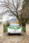 White vintage car with paper flower leaf garland swag attached.